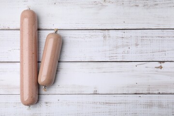 Delicious liver sausages on white wooden table, flat lay. Space for text
