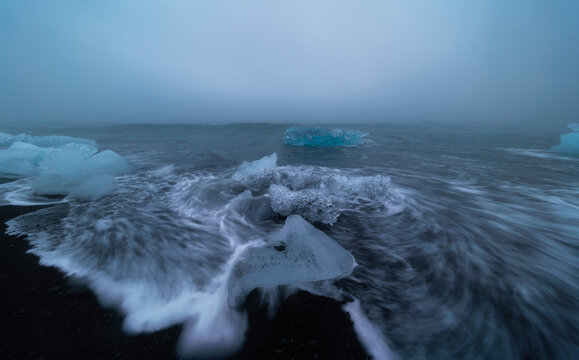 Block of ice being hit by a wave at J&ouml;kuls&aacute;rl&oacute;n beach, Iceland.