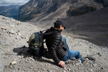 Tourist climbing down the steep slope of loose rocks on Plain of Six Glaciers track, lake Louise in...