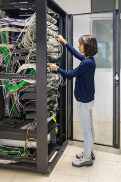Computer technician woman connecting cables in a rack