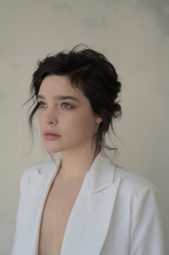 Portrait of a young beautiful brunette woman in a white suit.