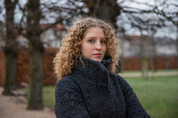 Portrait of a young girl with curly hair in a public park on a winter day.