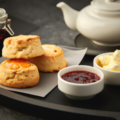 Traditional british teatime with scones and jam, clotted cream and teapot, close up on a tray generative ai illustration
