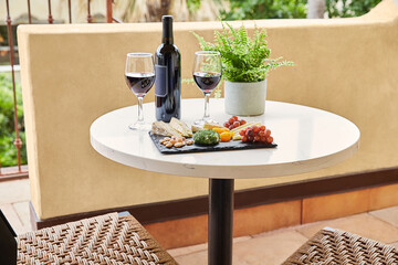 Bottle of wine and glasses with cheese plate on balcony