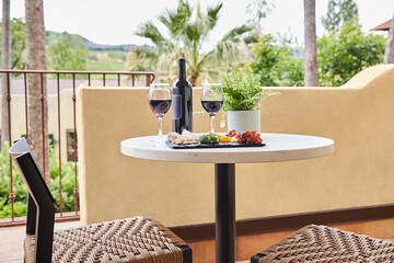 Bottle of wine and glasses with cheese plate on hotel balcony