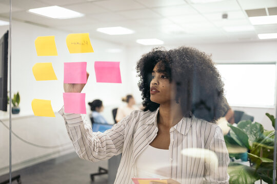 Business woman writing on post it during a meeting in the office