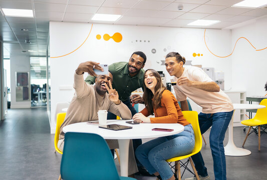 Coworkers taking a smartphone selfie during a break