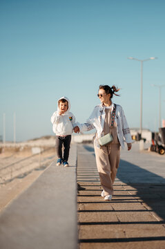 Mother stroll with son along beach.