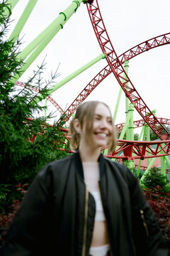 Happy woman at roller coaster in amusement park
