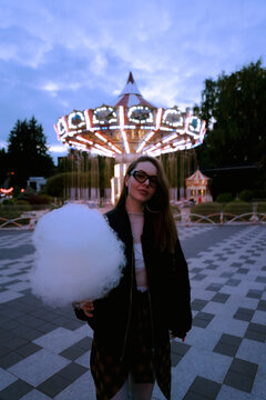 Girl eating candy cotton in amusement park
