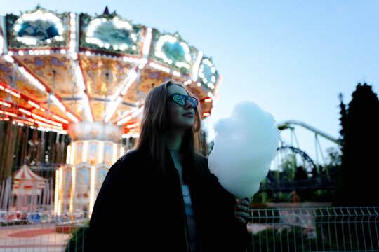 Girl eating candy cotton in amusement park

