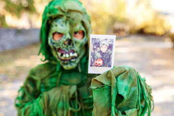 Boy in Halloween costume showing instant photo