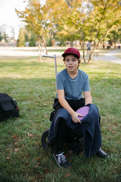 Portrait of boy sitting on disc golf cart.