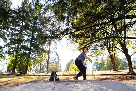 Young disc golfer teeing of with driver disc.