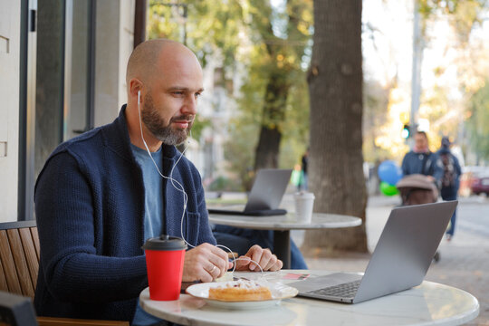 Man watching video on laptop during breakfast