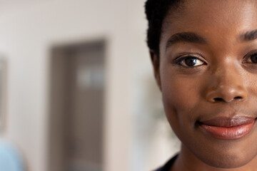 Half face portrait of smiling african american female doctor in hospital corridor with copy space