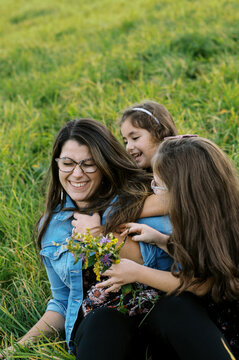 Two girls hugging their mother outdoors