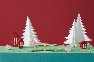 Holiday scene with cones, sledges, gift box and a paper house
