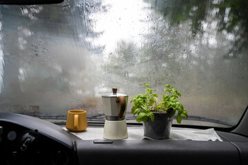 Coffee cup inside camper van on a rainy day
