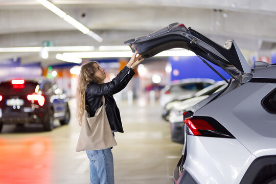 Woman with cart puts her purchases in car trunk