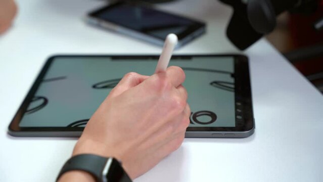 Person hand using bluetooth pencil draws good sketch on modern tablet screen. Drawer checks progress of drawing process. Camera shoots