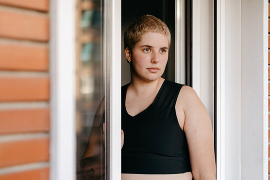 Positive non binary person in binder standing near window