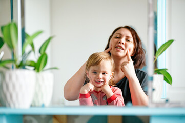  kid and mature mother exercises facial expressions 
