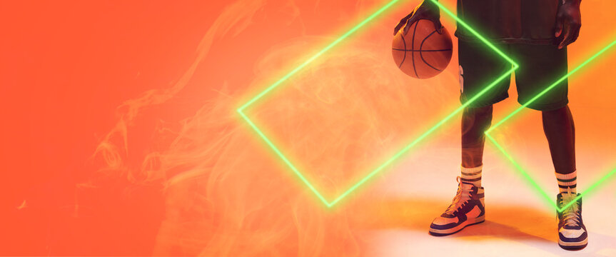 Low section of african american basketball player with ball by rectangles on orange background