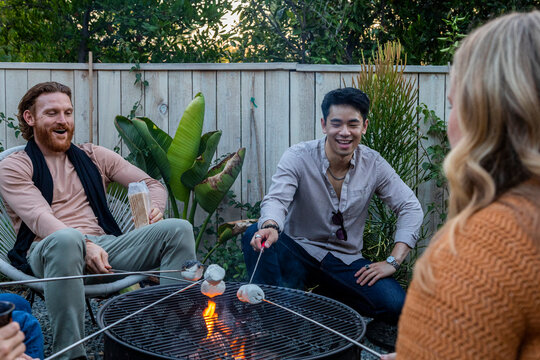 Friends roasting marshmallows and hanging out in a backyard