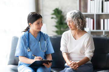 Focused doctor in glasses write diagnosis symptoms of mature woman patient in medical case.