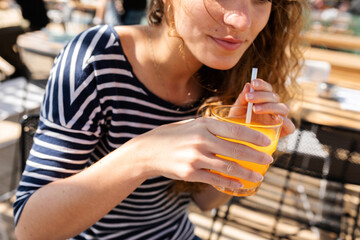 Crop woman drinking juice at terrace