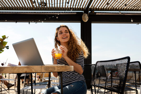Woman drinking juice whit laptop at terrace bar