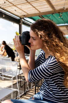 Young woman taking pics at terrace bar