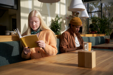 Girl absorbed in reading book during the break in cafe