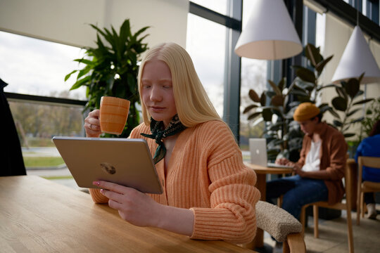 Woman drinking hot beverage using tablet