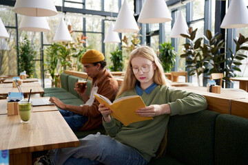 Focused woman reading novel in cafe