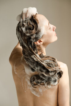 Beautiful young woman with her back with soapy hair