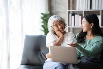 Young woman with mother using laptop at home, happy family time..