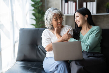 Young woman with mother using laptop at home, happy family time..