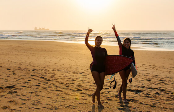 Happy female surfers showing gestures on beach