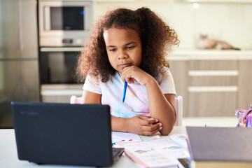 Teenager girl studying with laptop at home