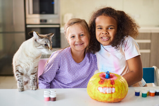 Child girls are photographed with a pumpkin for the Halloween holiday