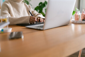 Woman using graphic tablet by laptop at office 