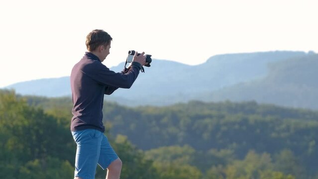Hiker photographer taking pictures of morning nature in summer mountains