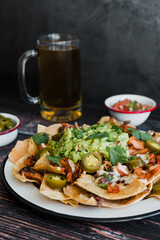 Mexican Nachos with cheese or tortilla chips with meat, avocado and beer, tex mex food in Mexico America