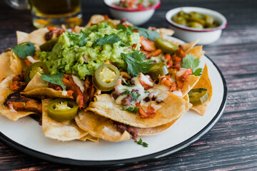 Mexican Nachos with cheese or tortilla chips with meat, avocado and beer, tex mex food in Mexico America