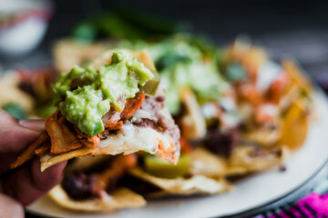 hand of man with mexican nachos with cheese meat and jalapeno peppers, man's hand in Mexico Latin America