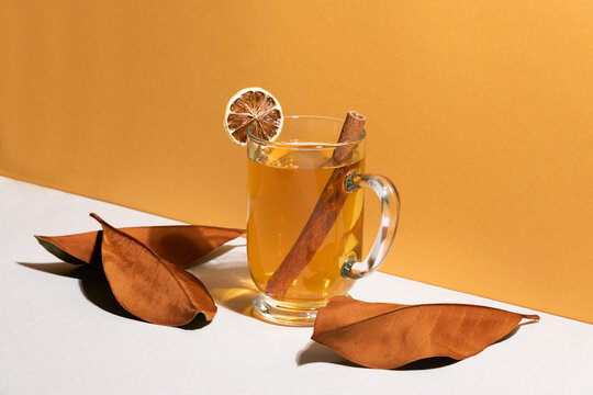 Hot golden tea with dried leaves and a cinnamon stick.