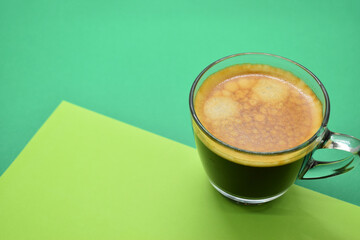 glass of hot black coffee put on green background