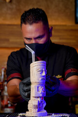 bartender with mask preparing cocktail at a bar counter